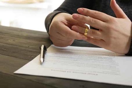 a man removing his wedding ring and signing a paper